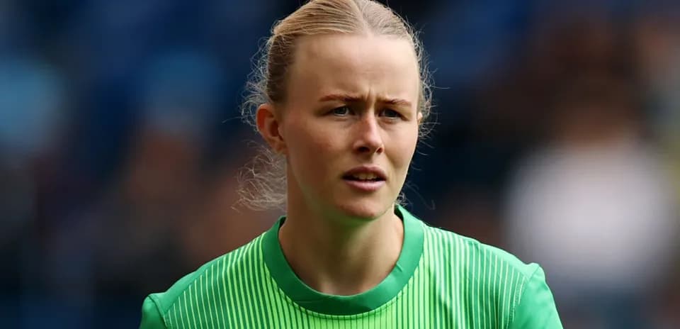 Female goalkeeper in green kit looking focused