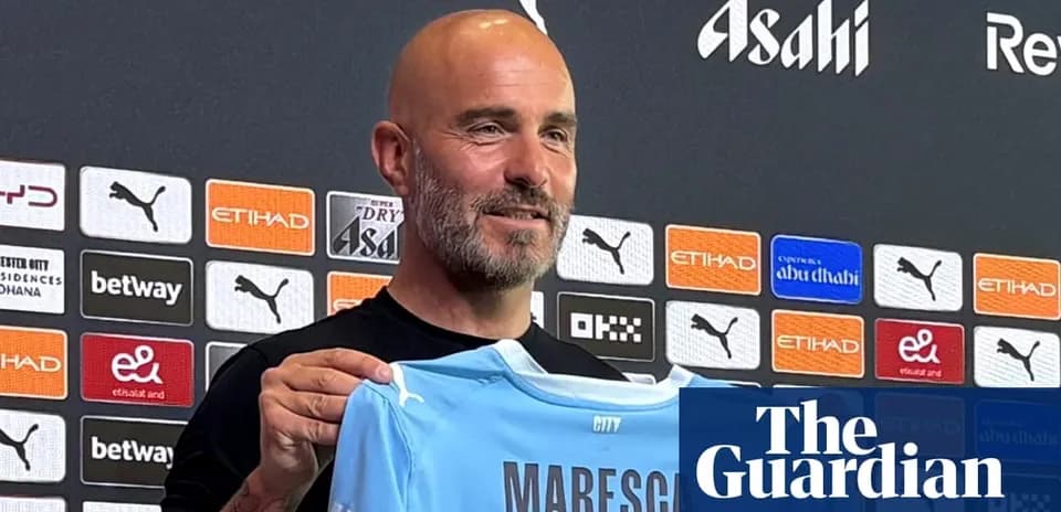 Manager holding a Manchester City jersey at press conference