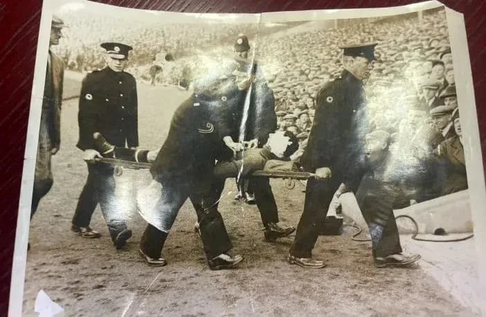 Four men carrying an injured person on a stretcher
