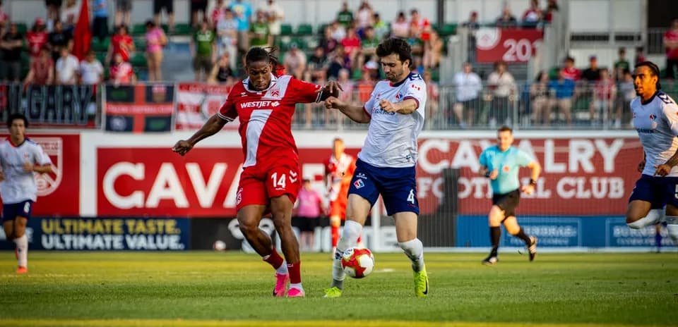 Cavalry FC player tackling Supra du Quebec opponent