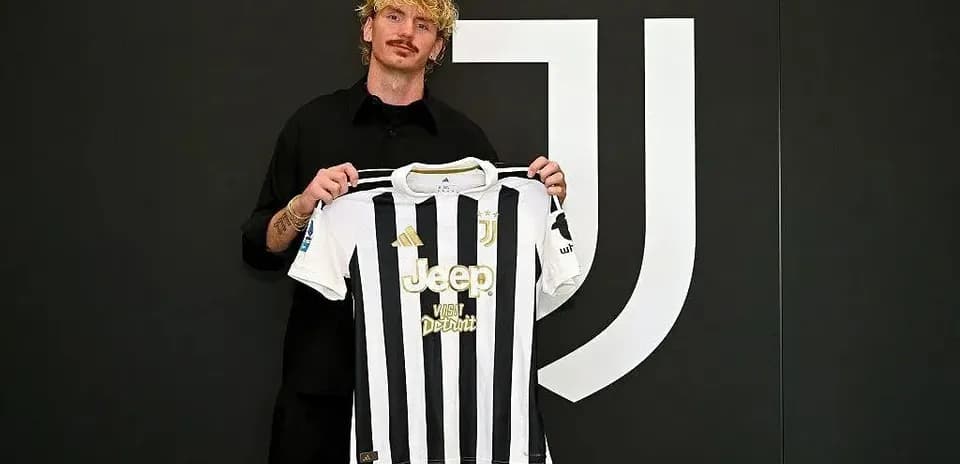 Player holding Juventus jersey in front of logo