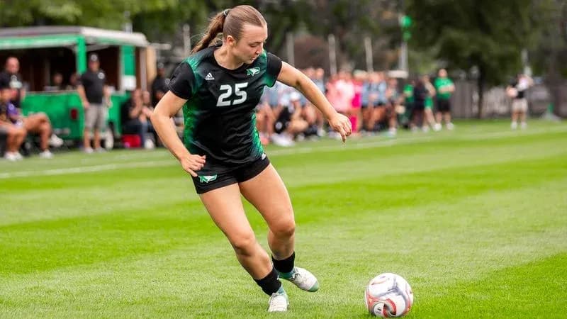 Player number 25 kicking a soccer ball on field