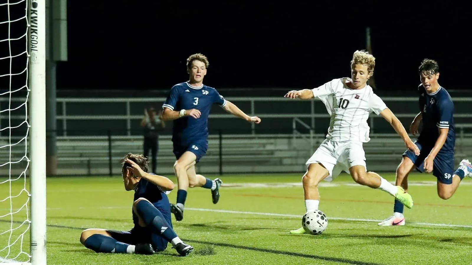 Player attempting to score as goalkeeper defends goal Player attempting to score as goalkeeper defends goal