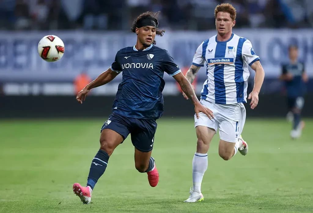 Player in blue jersey dribbling the ball past opponent Player in blue jersey dribbling the ball past opponent