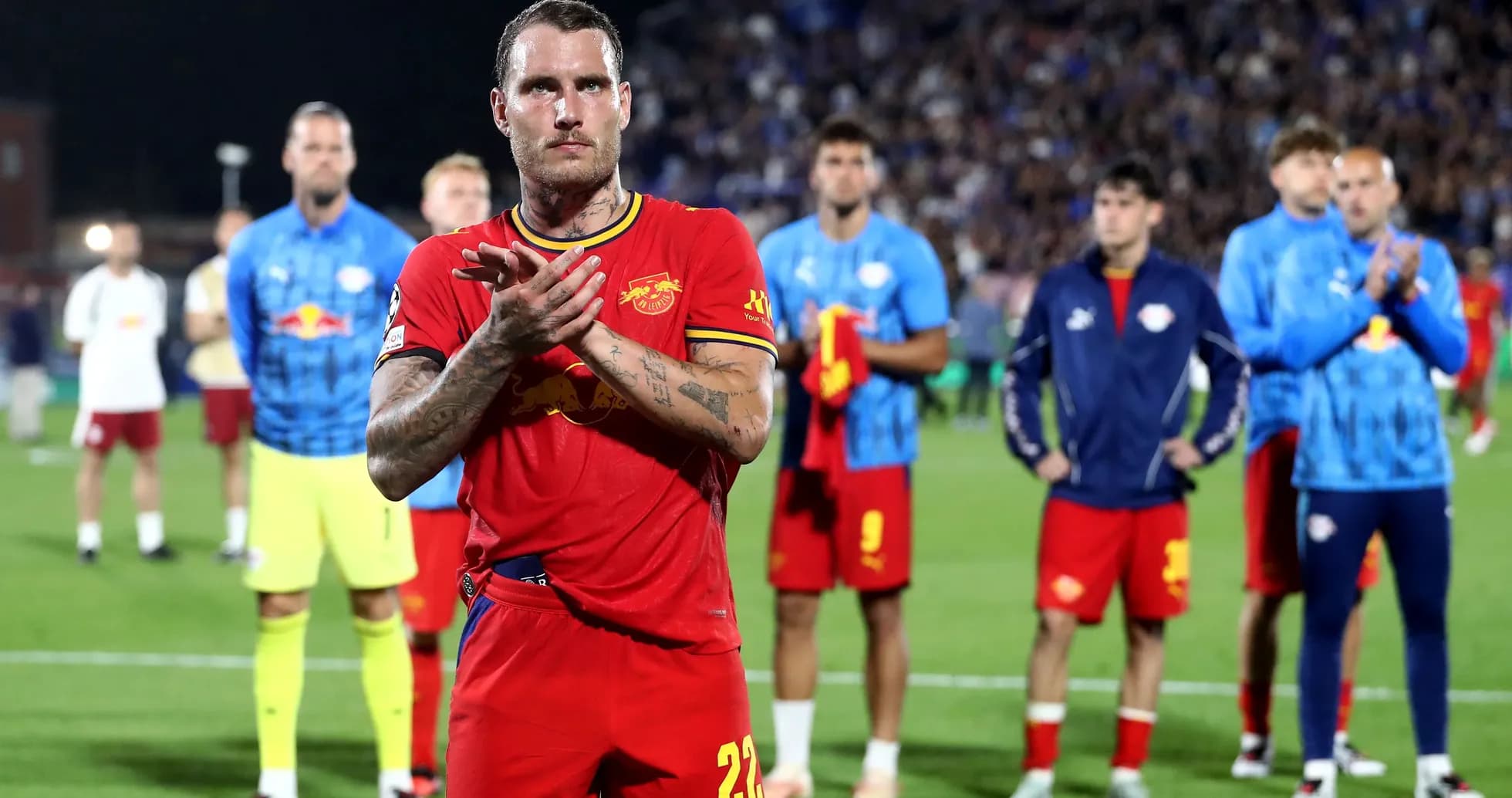Player applauding with teammates in background after match Player applauding with teammates in background after match