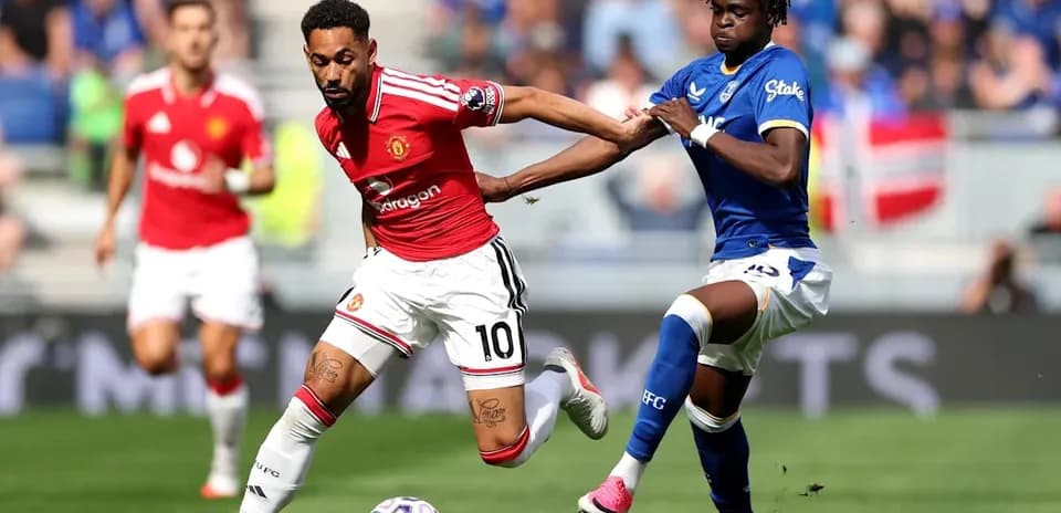 Player in red dribbling while being challenged by opponent Player in red dribbling while being challenged by opponent