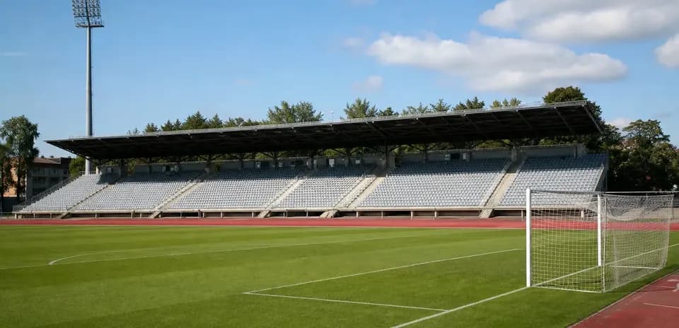 Empty football stadium with green pitch and bleachers Empty football stadium with green pitch and bleachers