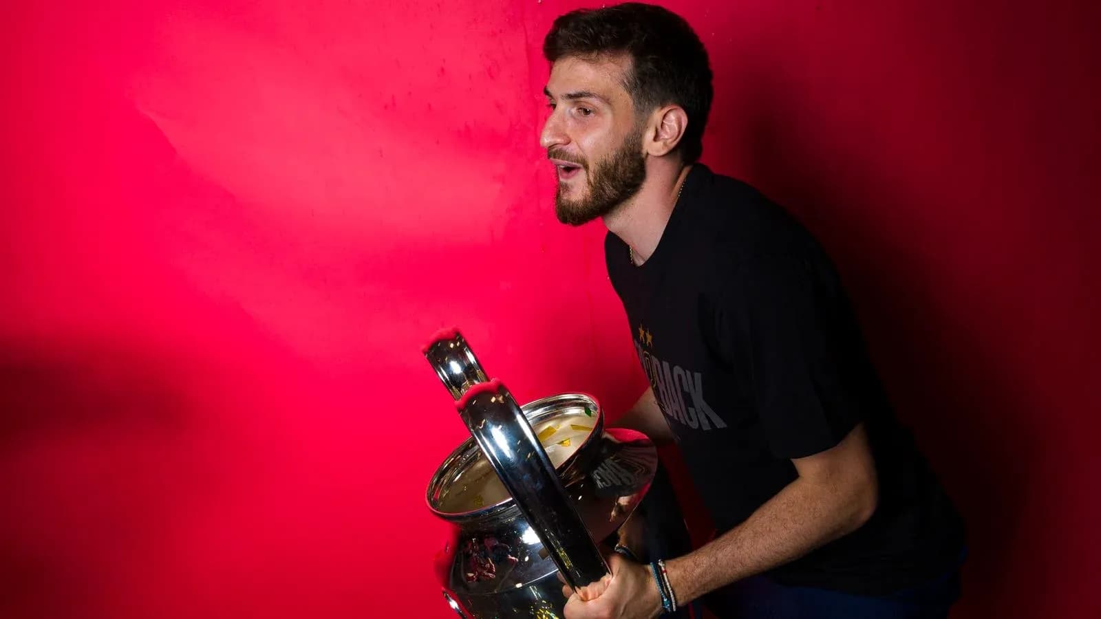 Player celebrating with a trophy against pink backdrop Player celebrating with a trophy against pink backdrop