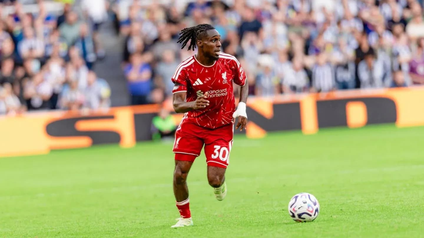 Player in red kit running with ball on field Player in red kit running with ball on field
