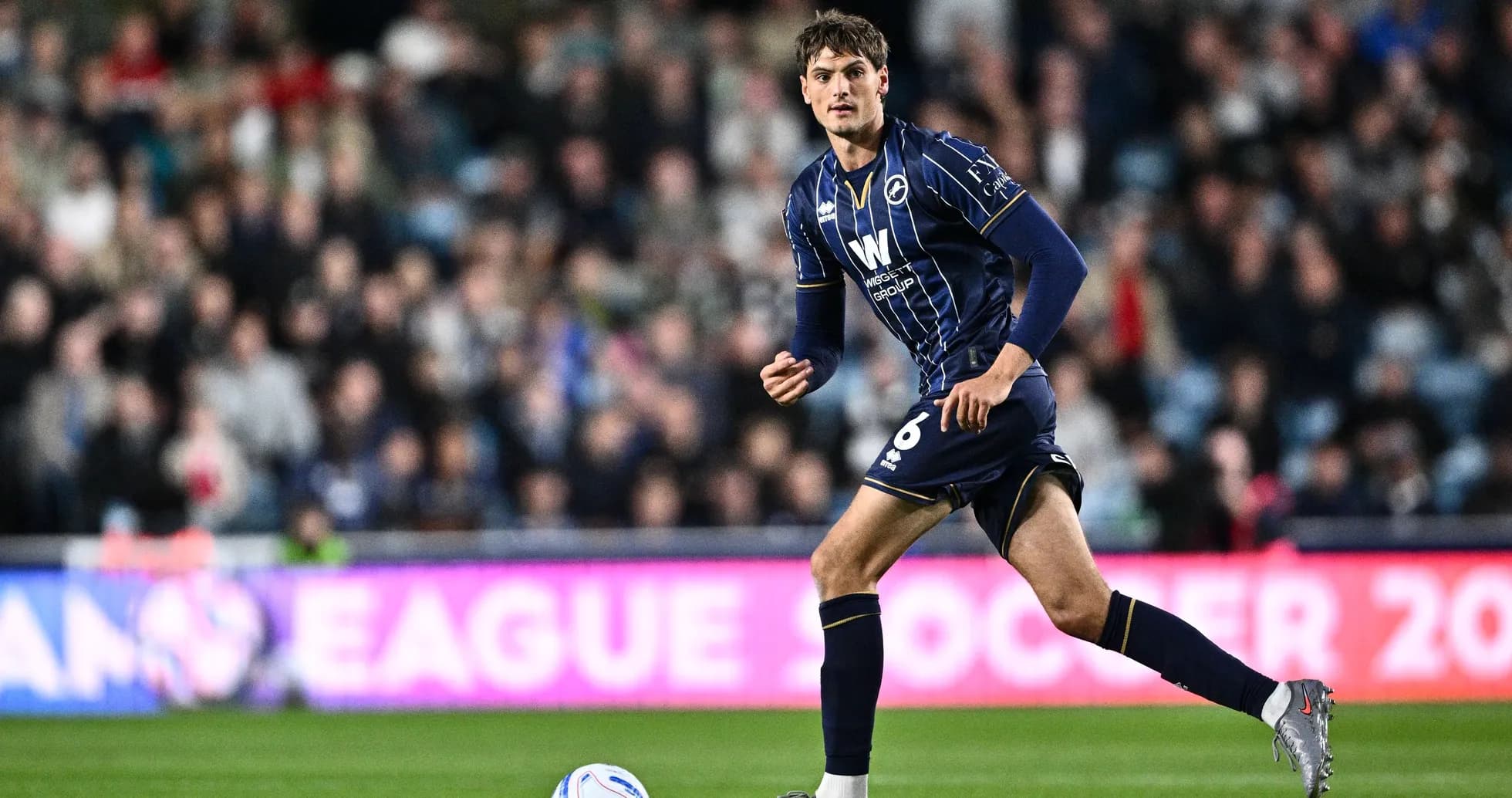 Player in blue kit running on the field Player in blue kit running on the field