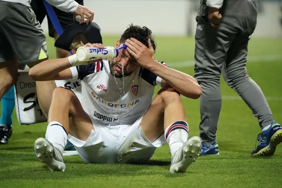 Player sitting on pitch pouring water on forehead Player sitting on pitch pouring water on forehead