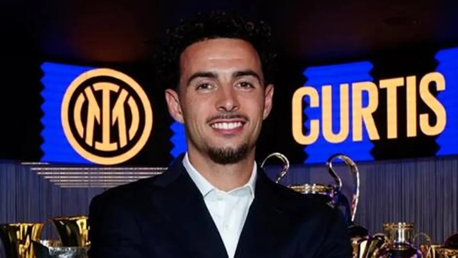 Player posing with trophies and club logo backdrop Player posing with trophies and club logo backdrop