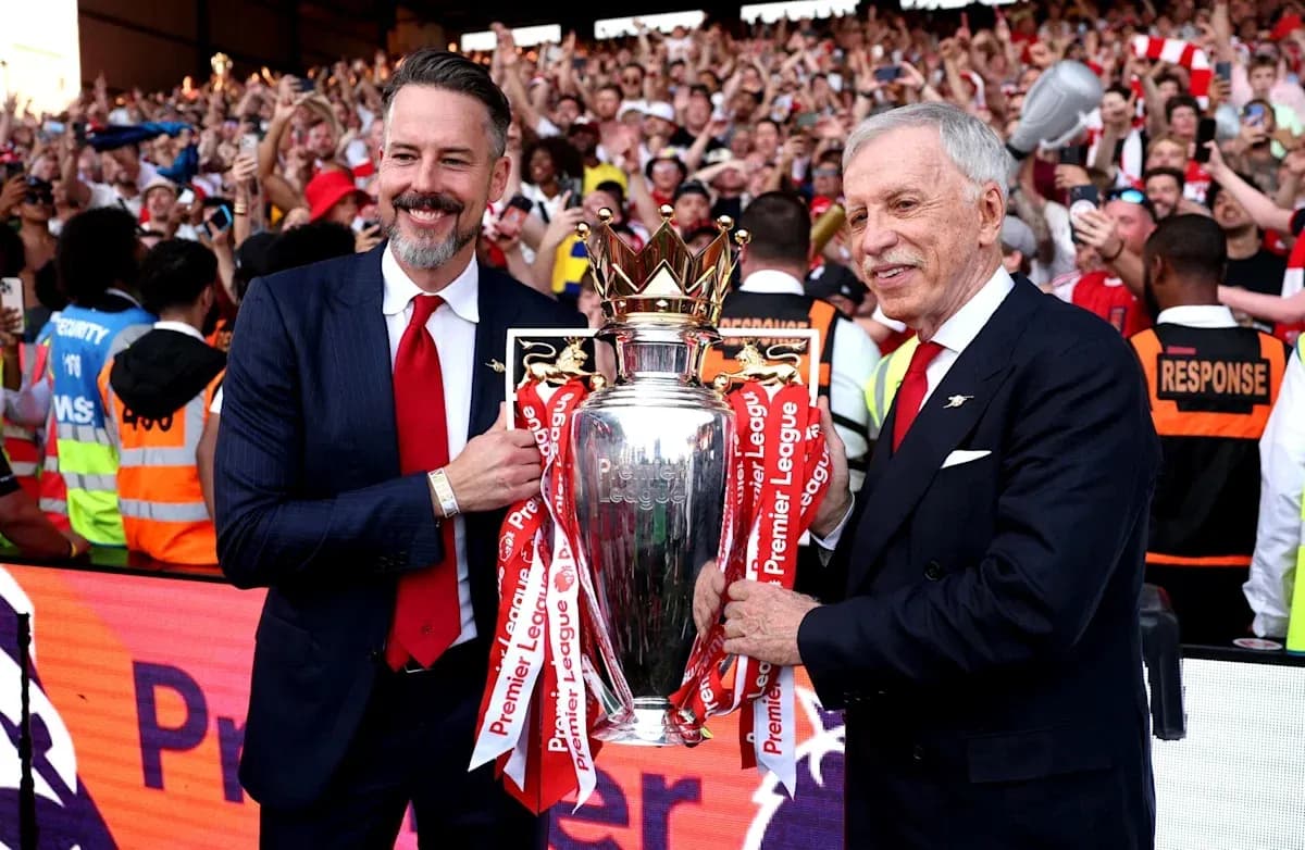 Two officials holding Premier League trophy with fans celebrating Two officials holding Premier League trophy with fans celebrating