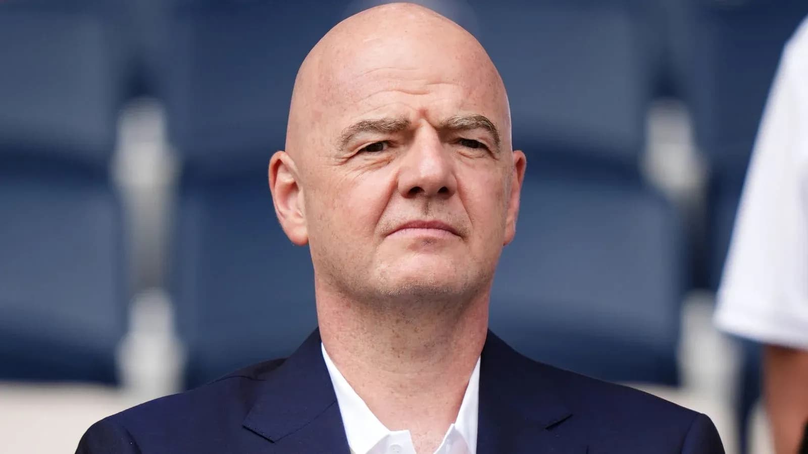 Man in a suit seated in stadium stands Man in a suit seated in stadium stands