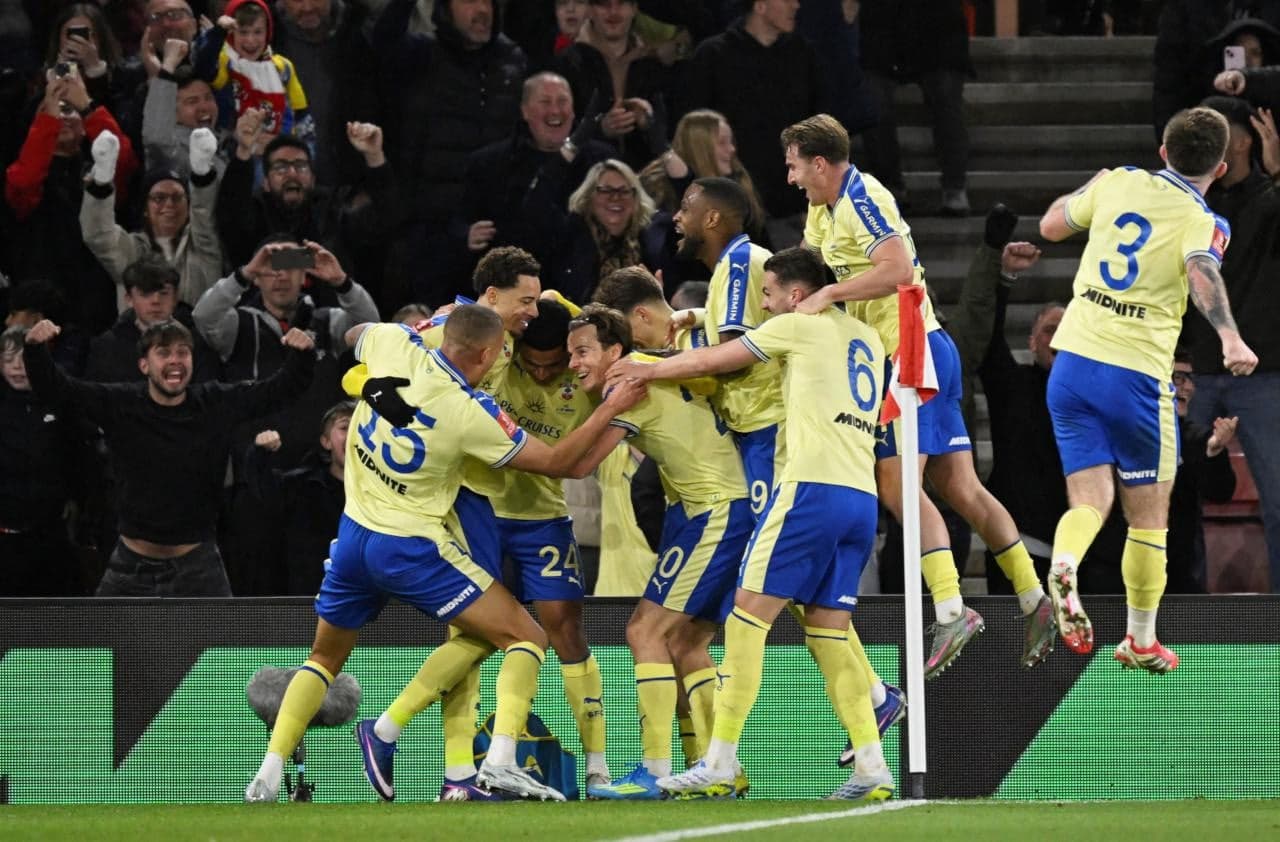 Players celebrating a goal with fans in background Players celebrating a goal with fans in background