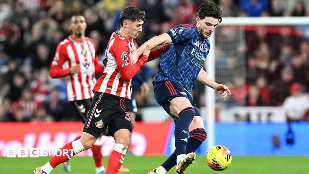 Sunderland player challenging Arsenal player for the ball Sunderland player challenging Arsenal player for the ball