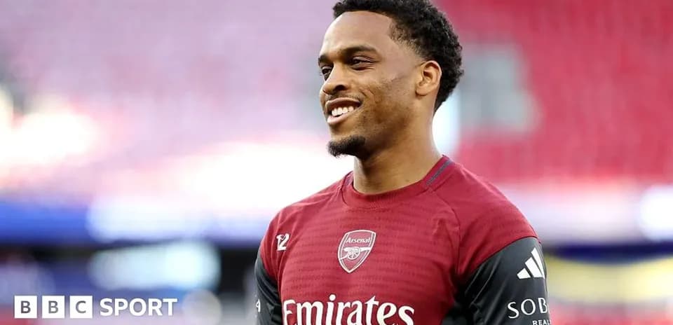 Player in Arsenal training kit smiling on pitch Player in Arsenal training kit smiling on pitch