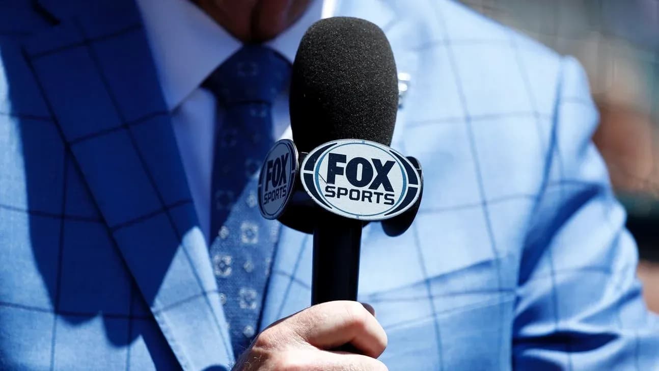 Person holding a FOX Sports microphone in suit Person holding a FOX Sports microphone in suit