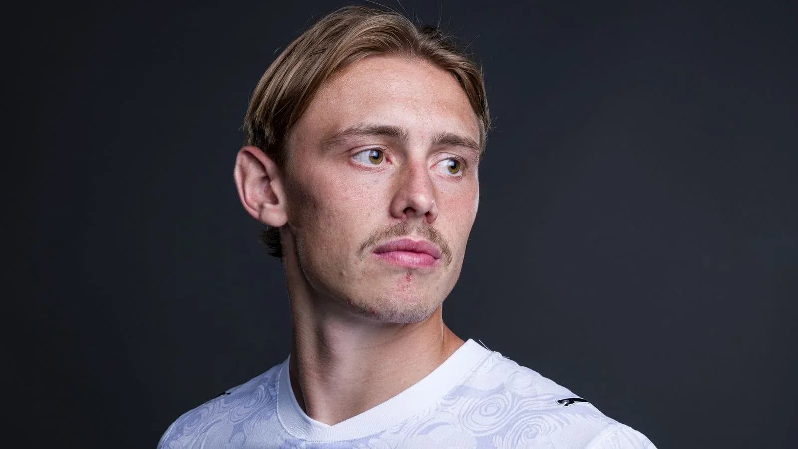 Player posing in white jersey against dark background Player posing in white jersey against dark background
