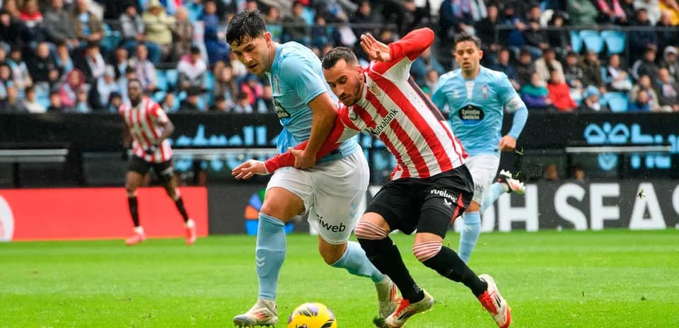 Athletic Club player challenging Celta Vigo opponent Athletic Club player challenging Celta Vigo opponent