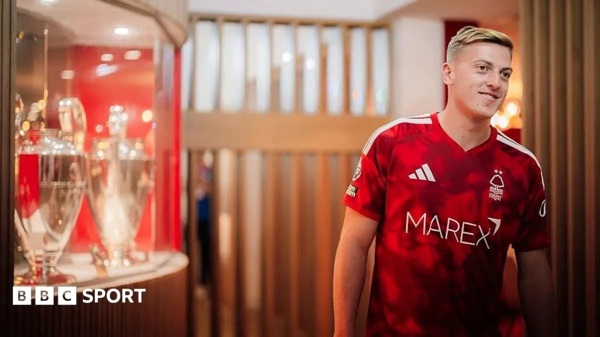 Player in Nottingham Forest jersey near trophies display Player in Nottingham Forest jersey near trophies display