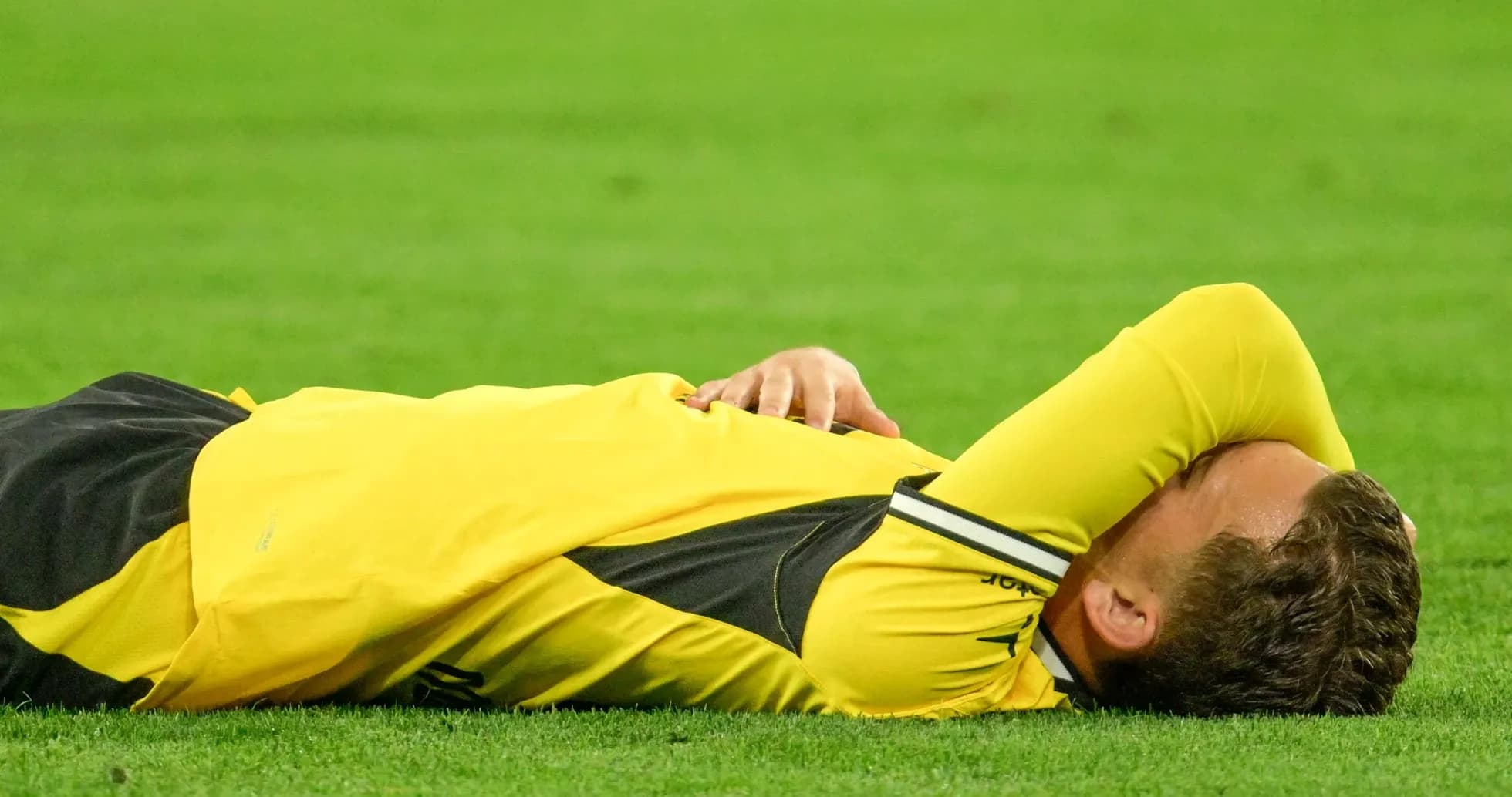 Player lying on field with hands over face Player lying on field with hands over face