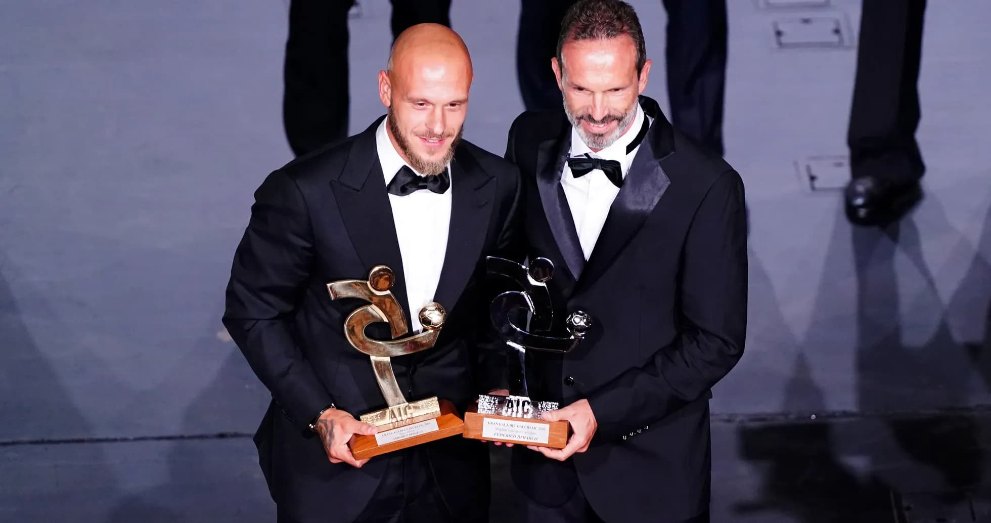 Two men in tuxedos holding awards at event Two men in tuxedos holding awards at event
