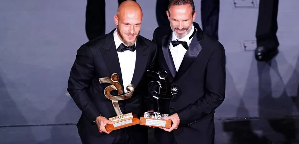 Two men in tuxedos holding awards at event Two men in tuxedos holding awards at event