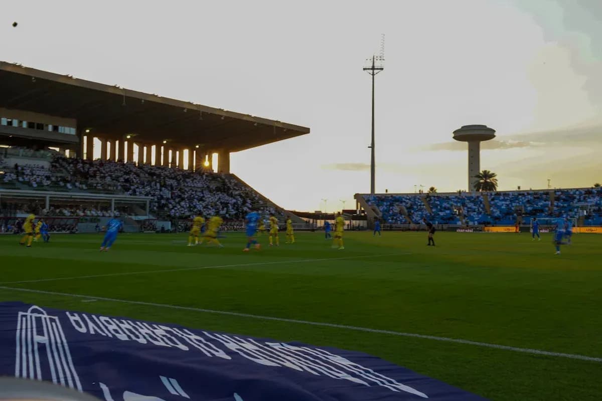 Players competing during a soccer match at sunset Players competing during a soccer match at sunset