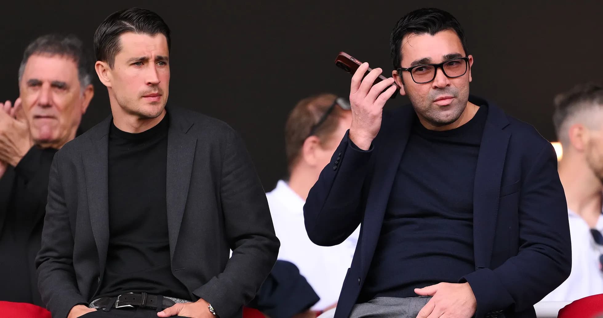 Two men seated in stands during an event Two men seated in stands during an event