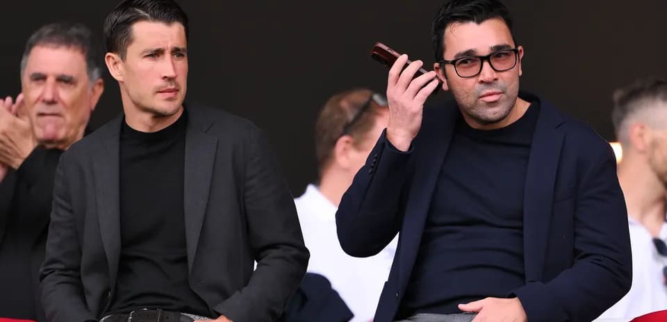 Two men seated in stands during an event Two men seated in stands during an event