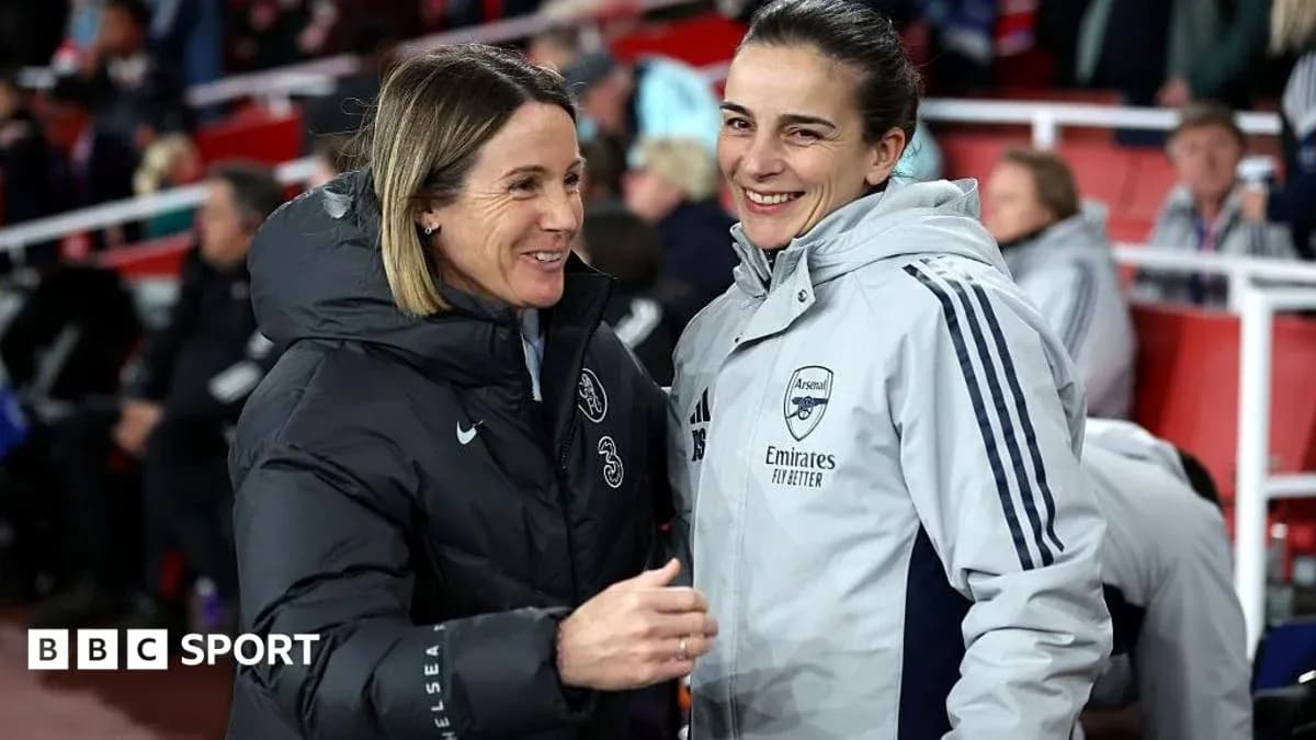 Two coaches smiling and conversing on sidelines Two coaches smiling and conversing on sidelines