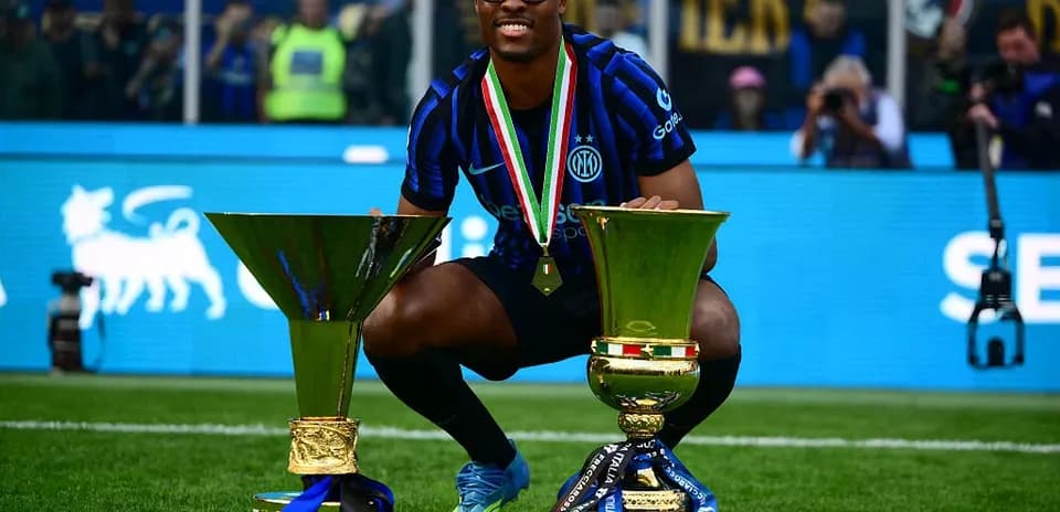 Player celebrating with two trophies on the field Player celebrating with two trophies on the field