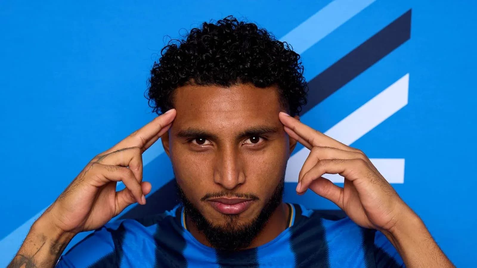 Player posing with fingers on temples against blue background Player posing with fingers on temples against blue background