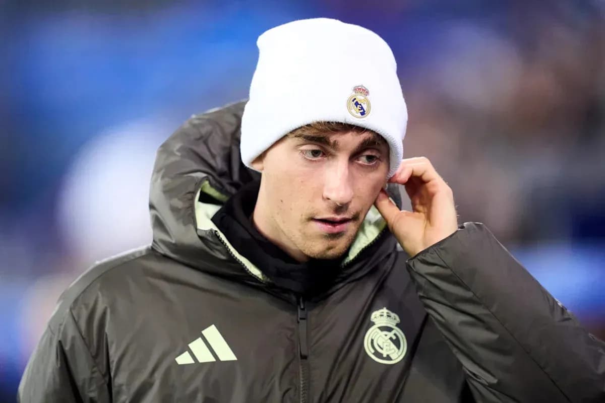 Player wearing Real Madrid jacket and beanie on pitch Player wearing Real Madrid jacket and beanie on pitch