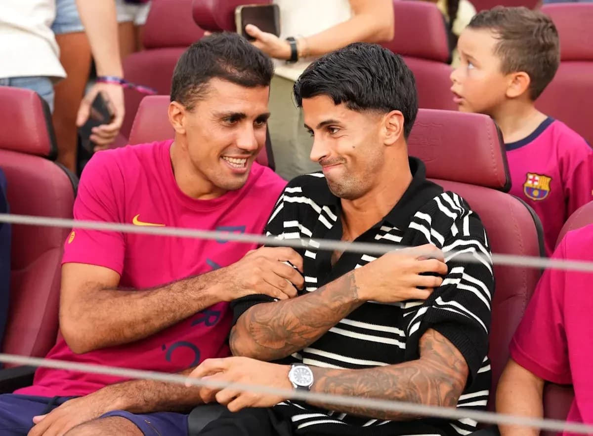 Two football players seated, smiling and interacting Two football players seated, smiling and interacting