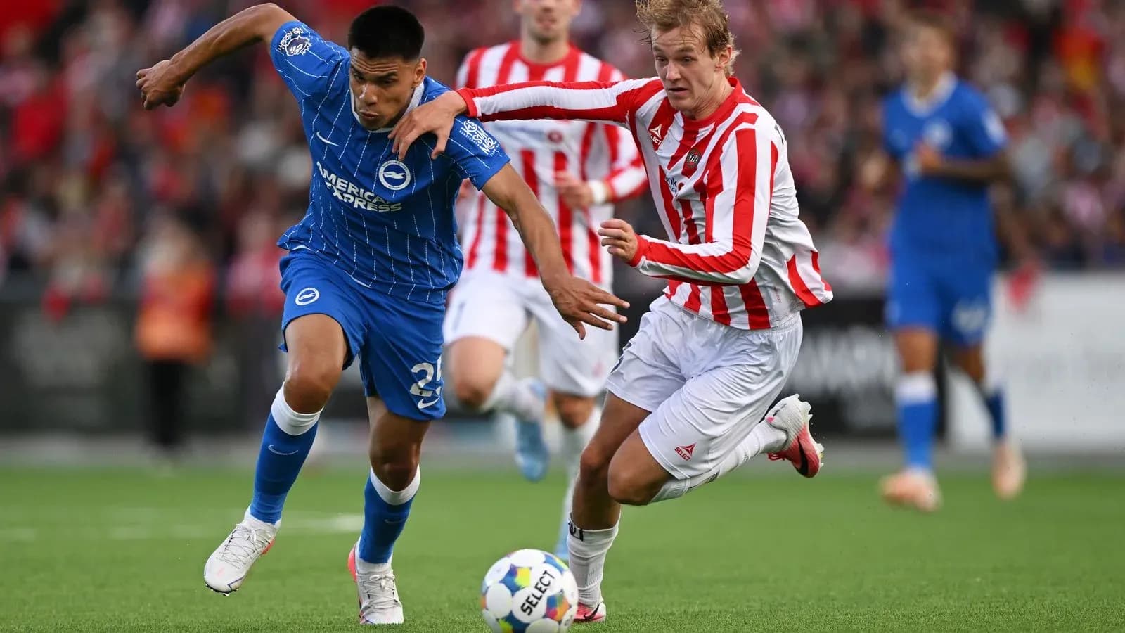 Player in blue and player in red competing for the ball Player in blue and player in red competing for the ball
