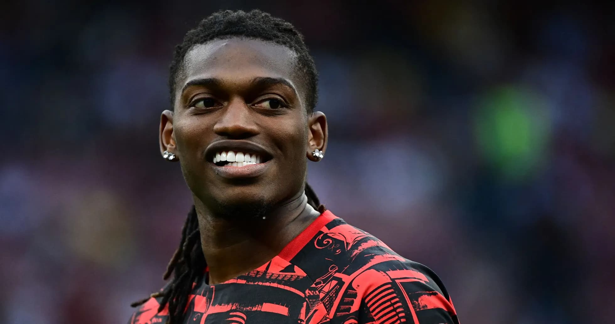 Player smiling in red patterned jersey on field Player smiling in red patterned jersey on field
