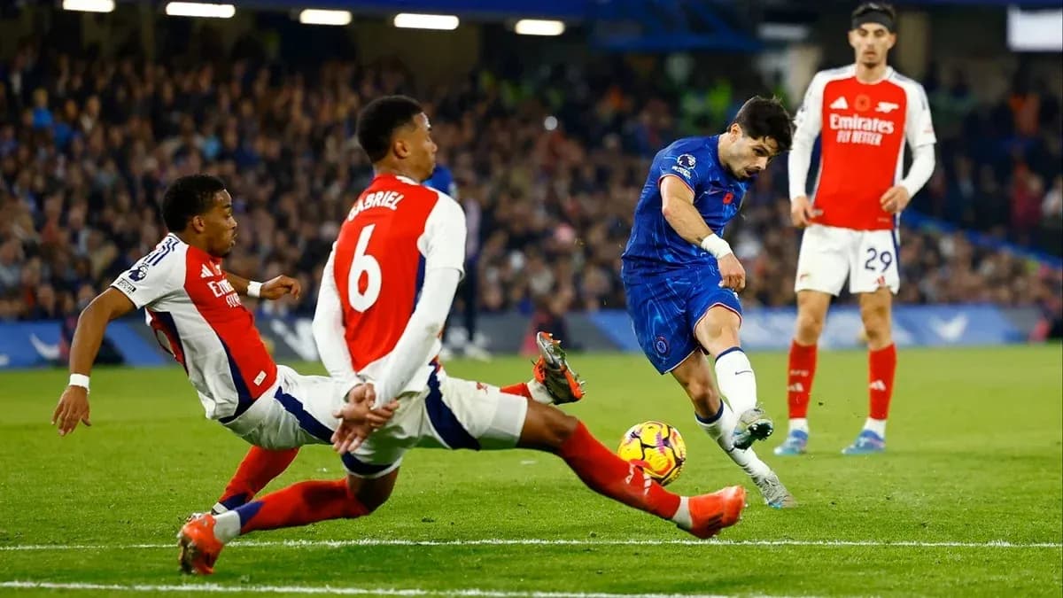 Chelsea player shooting at goal with Arsenal defenders nearby Chelsea player shooting at goal with Arsenal defenders nearby