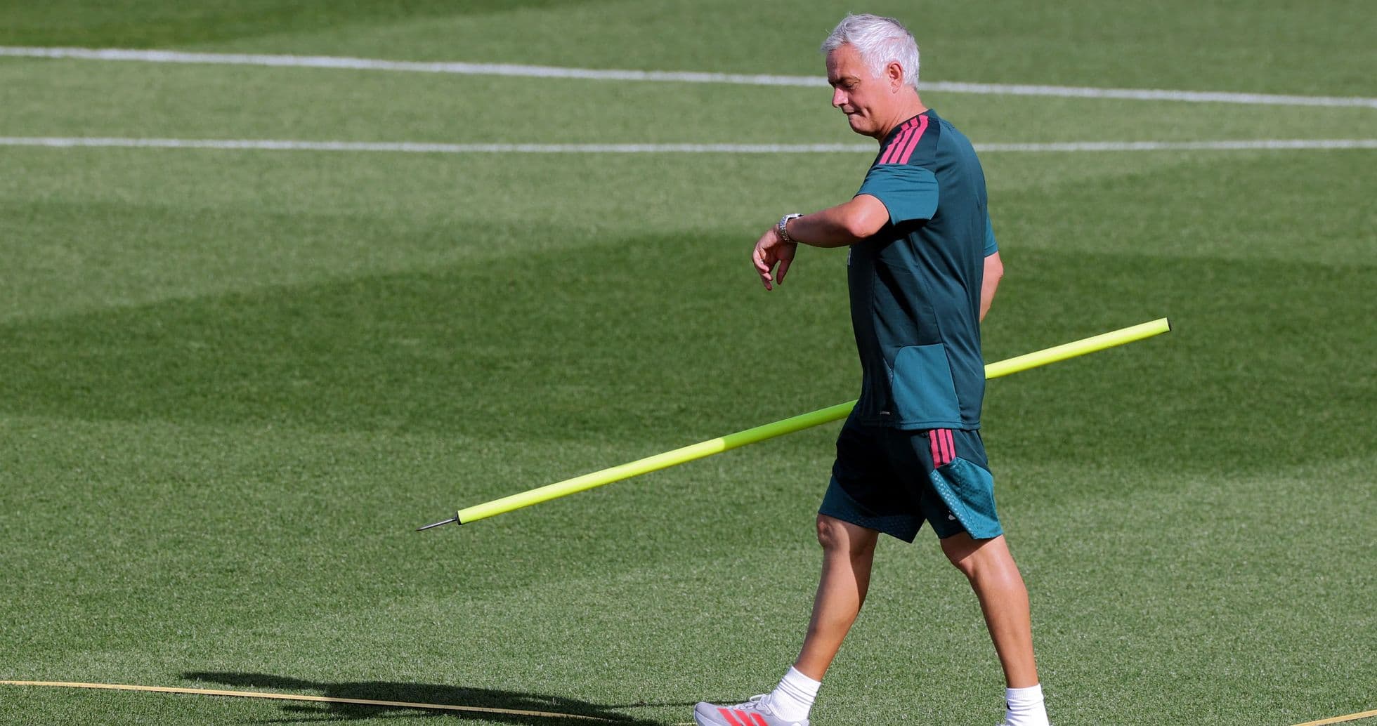 Coach walking on pitch holding training equipment Coach walking on pitch holding training equipment