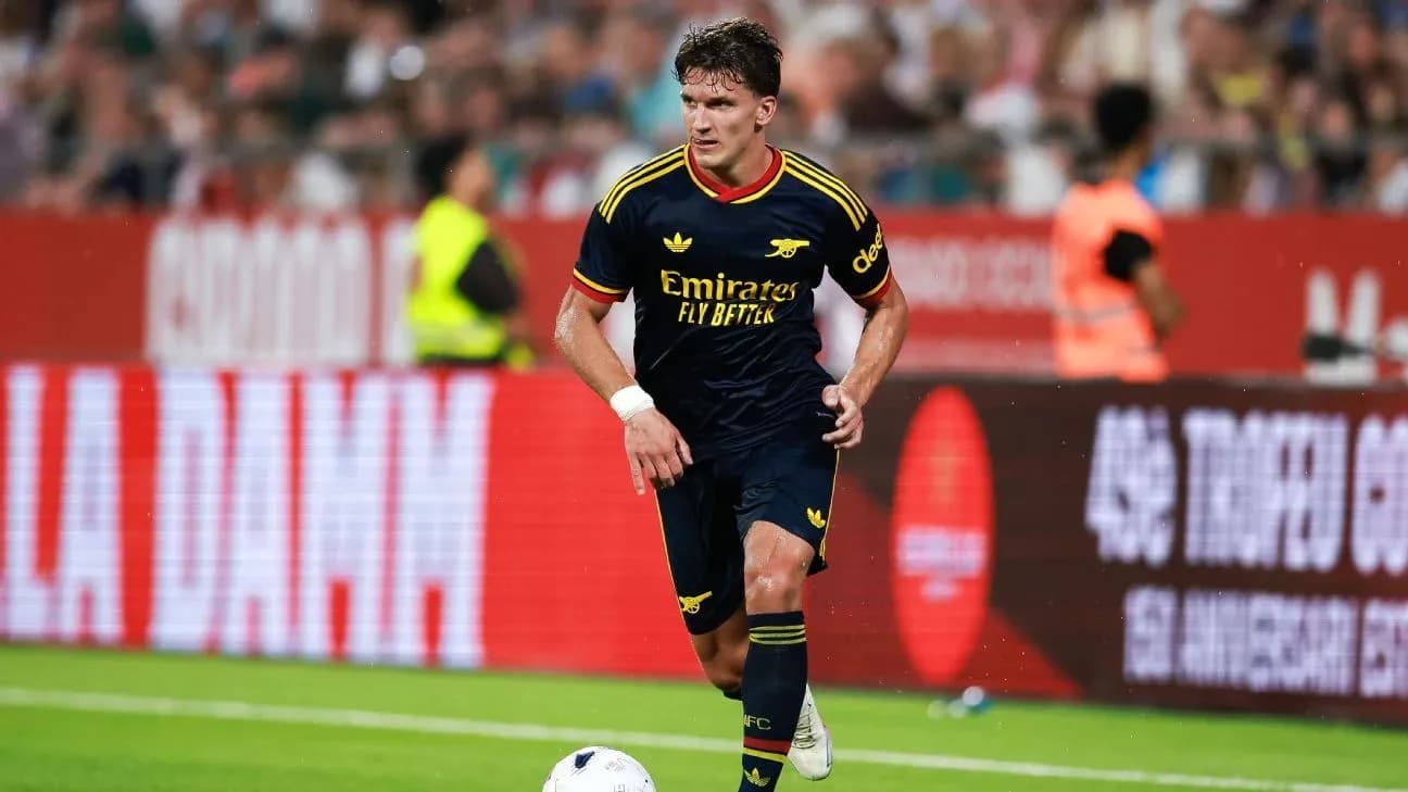 Player in Arsenal kit dribbling ball on pitch Player in Arsenal kit dribbling ball on pitch