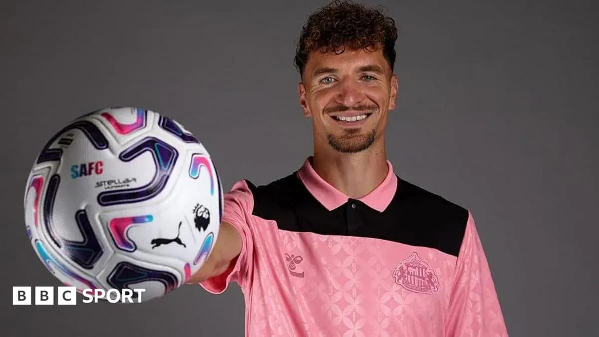 Player holding a football in team jersey Player holding a football in team jersey