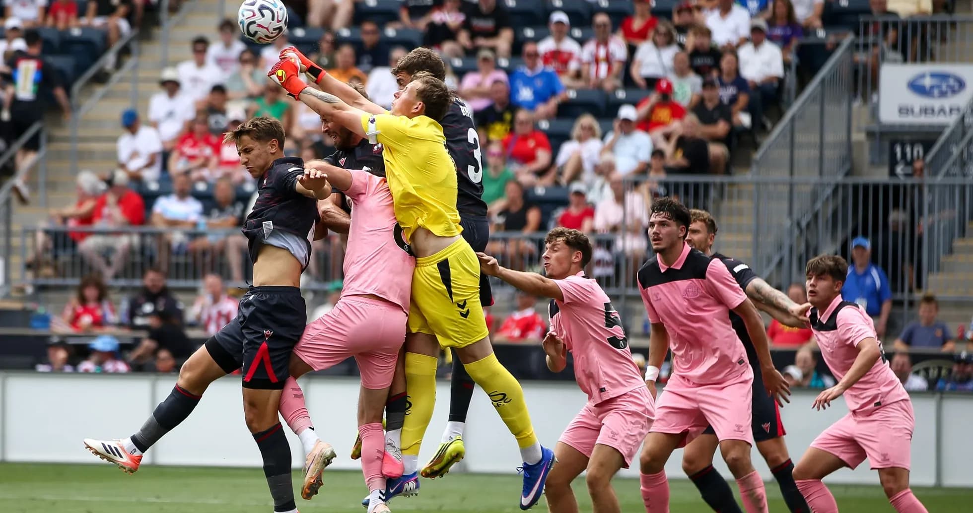 Goalkeeper catching the ball amid player crowding Goalkeeper catching the ball amid player crowding