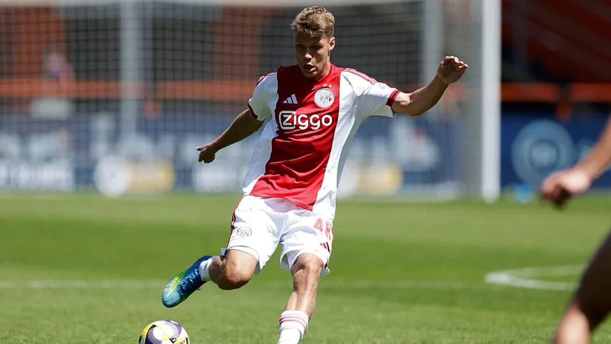 Player in Ajax kit kicking the ball on field Player in Ajax kit kicking the ball on field