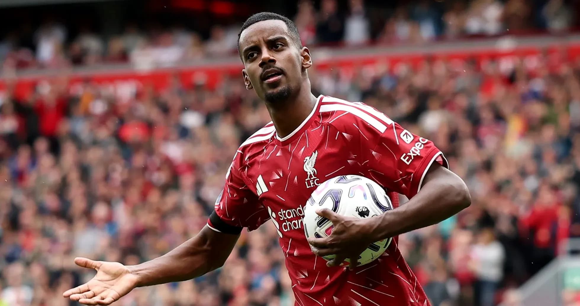 Player in Liverpool kit holding ball on pitch Player in Liverpool kit holding ball on pitch