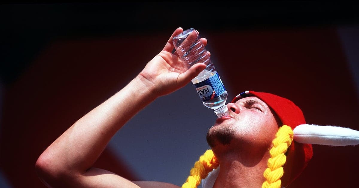 Person drinking water from a bottle during event Person drinking water from a bottle during event