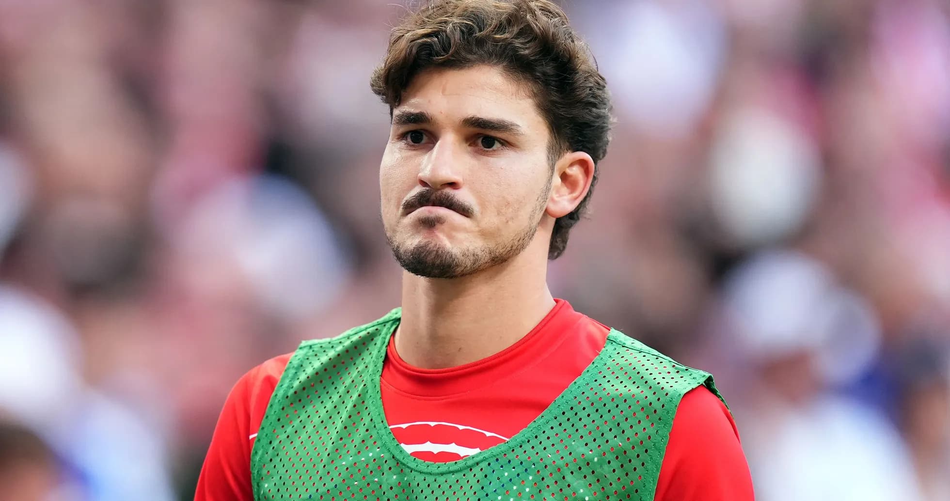 Player in training bib on sideline during match Player in training bib on sideline during match