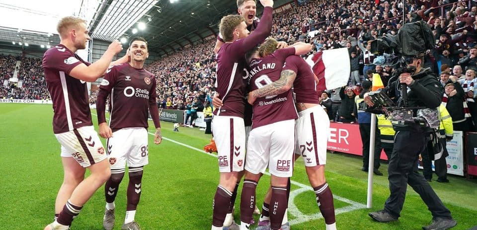 Hearts players celebrating a goal with fans in background Hearts players celebrating a goal with fans in background