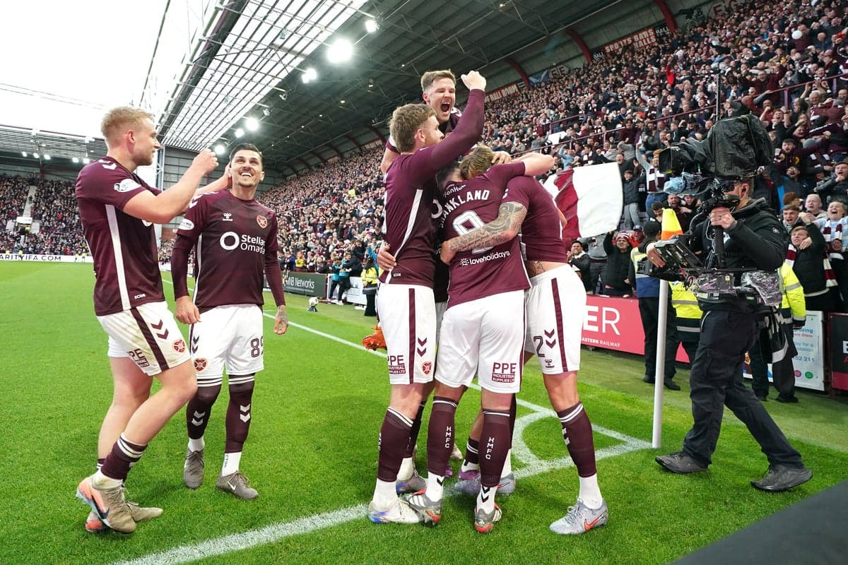 Hearts players celebrating a goal with fans in background Hearts players celebrating a goal with fans in background