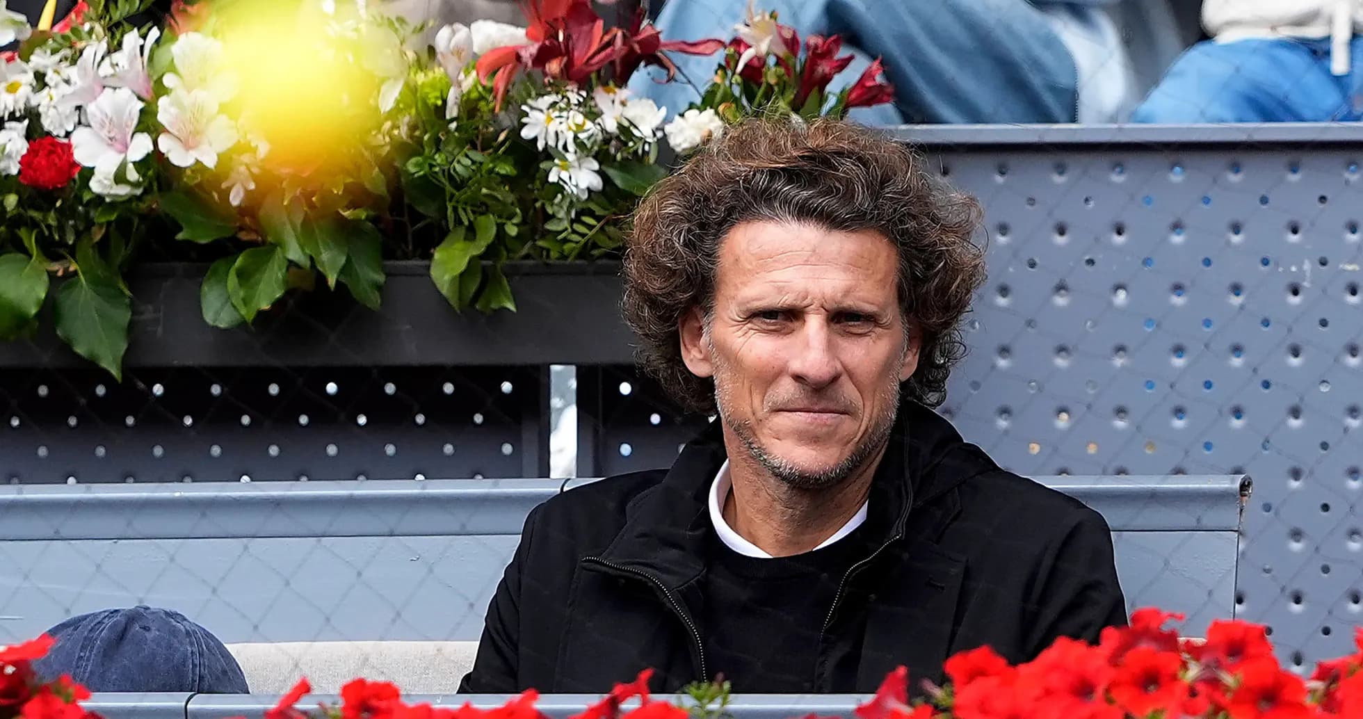 Man seated among flowers at a tennis event Man seated among flowers at a tennis event
